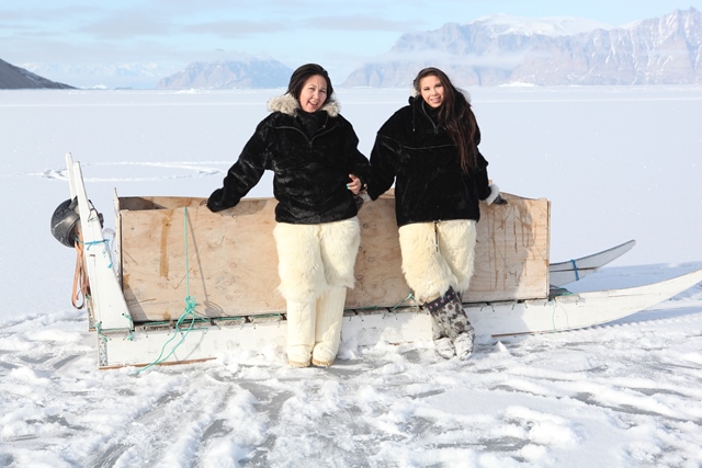 Sara and Pipaluk standing by the dog sledge box